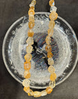 Necklace with orange and clear beads on a textured surface
