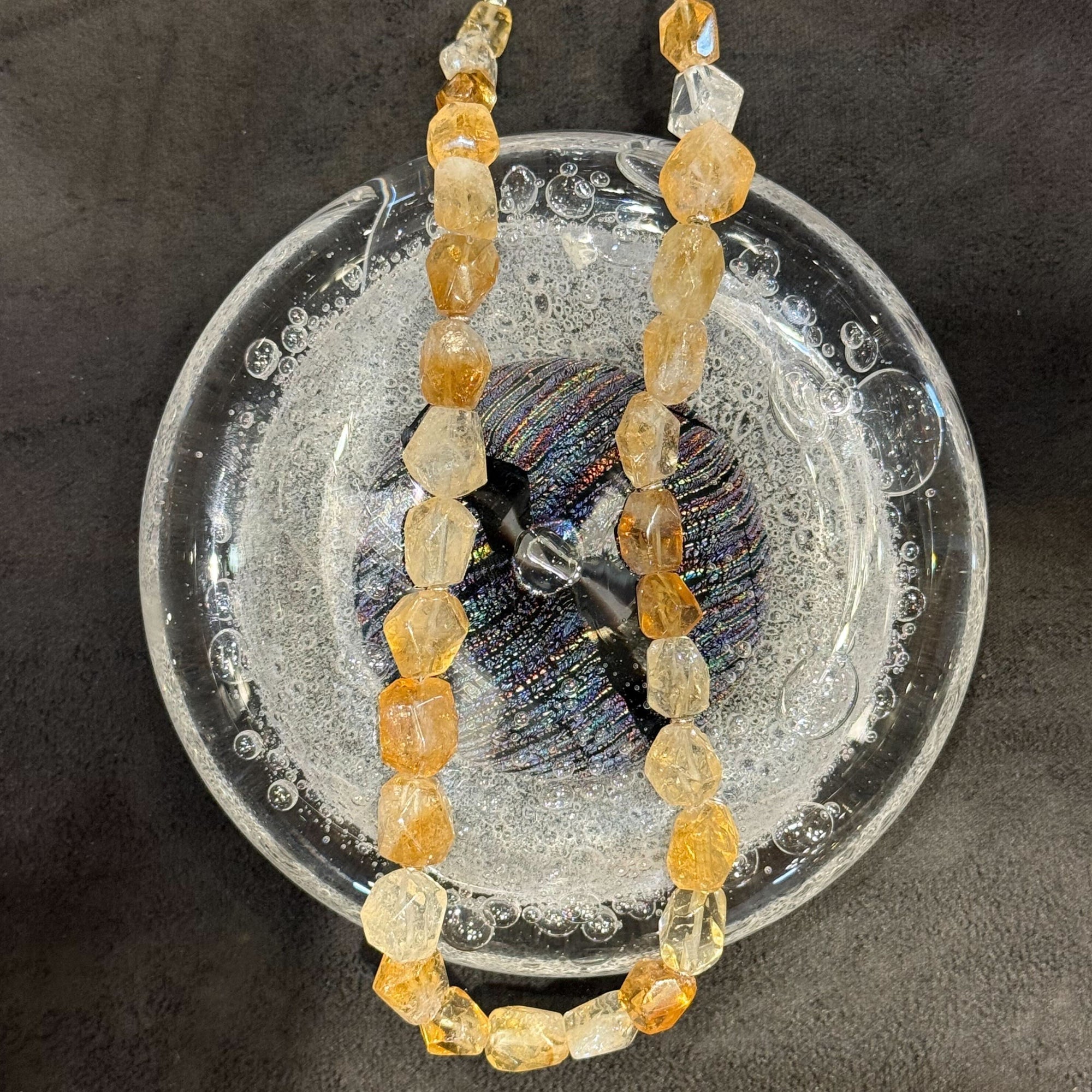 Necklace with orange and clear beads on a textured surface
