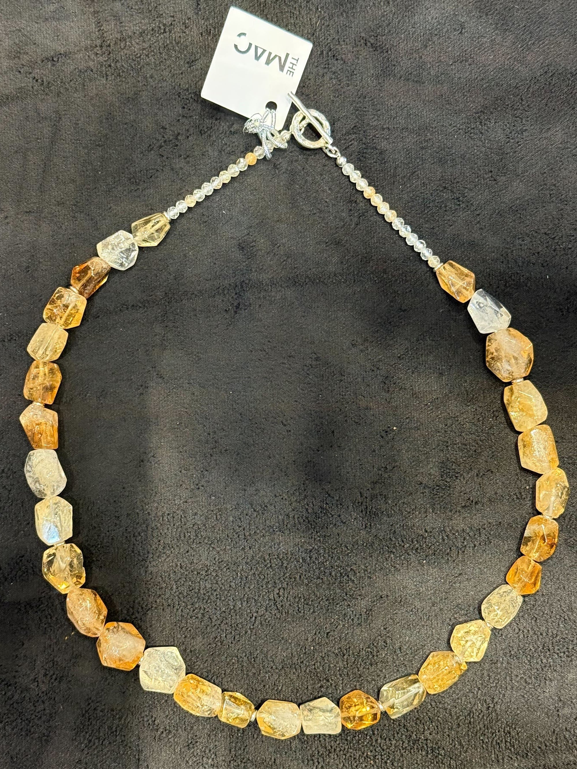 Necklace with multicolored beads and a tag on a dark background